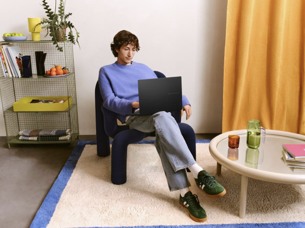A person sitting in a chair with an ASUS laptop in their lap.